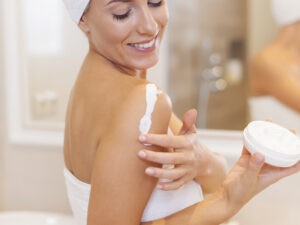 Woman moisturizes arm after the shower