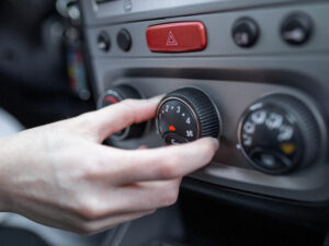 Woman hand turning on car air conditioning system, car air conditioner on off button close up view