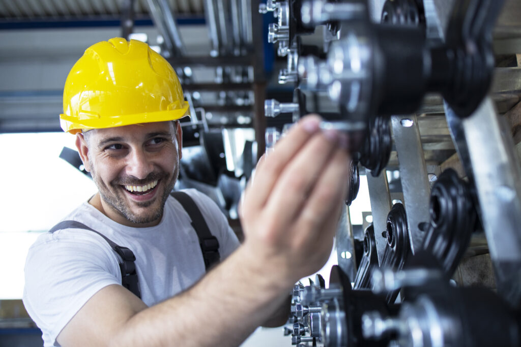 Worker inspecting parts for automobile industry in factory production line.