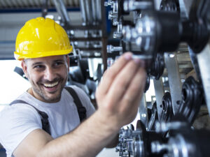 Worker inspecting parts for automobile industry in factory production line.